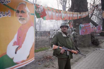 Indian paramilitary soldiers stand guard outside Sheri Kashmir cricket stadium where Prime Minister Narendra Modi, photograph on left, is expected to make campaign speech on Monday.