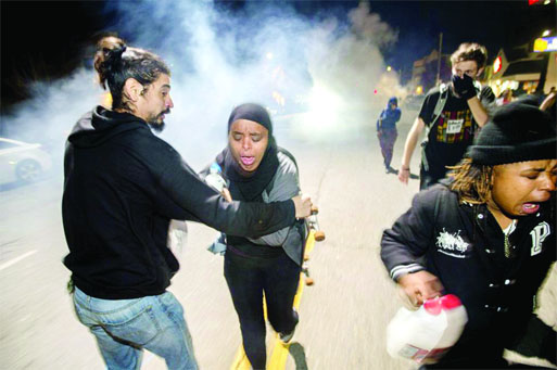 Protesters retreat while police officers deploy teargas to disperse a crowd comprised largely of student protesters during a protest against police violence in the US, in Berkeley, California on Sunday.