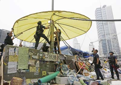 Police officers clear yellow umbrella and barricades at the occupied area outside government headquarters in Hong Kong on Thursday.
