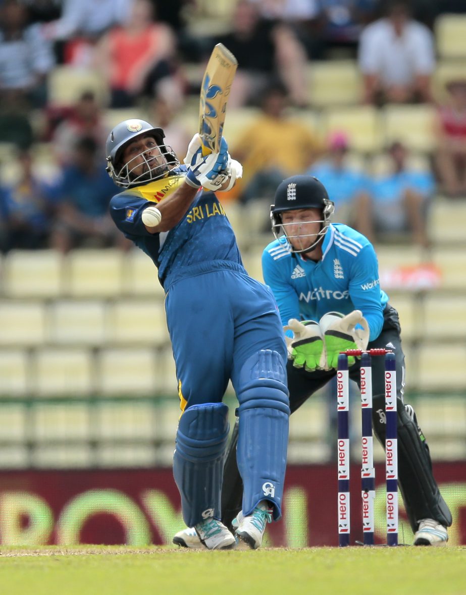 Sri Lankan batsman Tillakaratne Dilshan plays shot as England's wicketkeeper Jos Buttler watches during the sixth one day international cricket match between Sri Lanka and England in Pallekele, Sri Lanka on Saturday.
