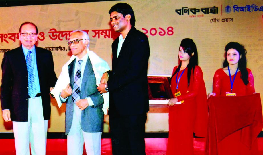 Director General of Bangladesh Institute of Development Studies Dr Mustafa Kamal Mujeri and Banik Barta Editor Hanif Mahmud, handing over a shawl and a crest to Prof Dr Wahiduddin Mahmud for his outstanding contributions to the country's economy at a cit