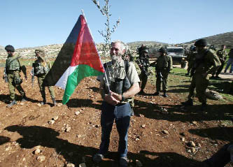 A man holds a Palestinian flag and a baby olive tree during a demonstration intended to plant 300 olive trees in the village of Turmus Aya near Ramallah, in the Israeli-occupied West Bank.