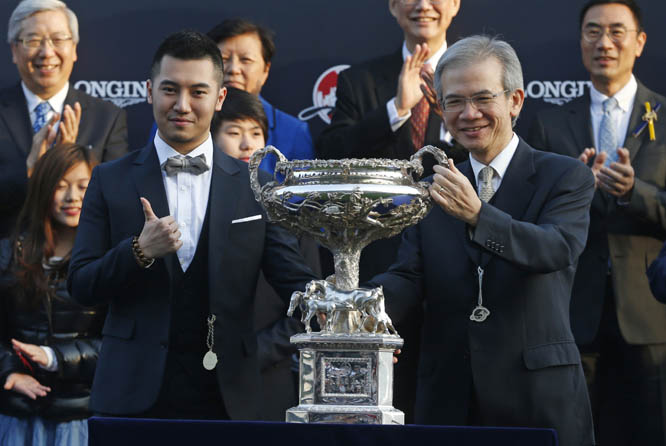 Cheng Ka Sing (left) son of Cheng Keung Fai the owner of Hong Kong horse Design on Rome celebrates with his trophy after winning the 2,000-meter Hong Kong Cup horse race at the Shatin race track in Hong Kong on Sunday.