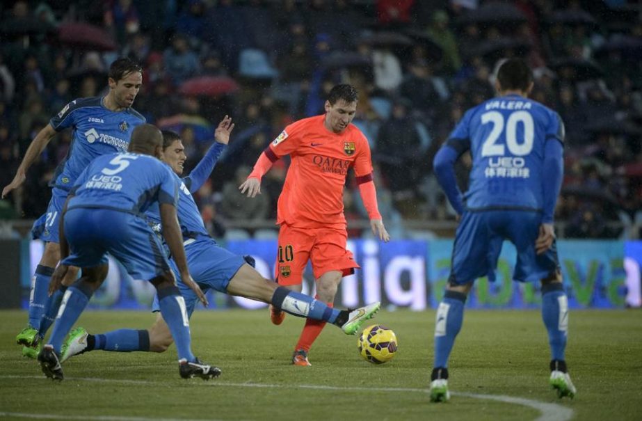 Getafe's Uruguayan defender Emiliano Velazquez vies with Barcelona's Argentinian forward Lionel Messi (C) during their Spanish league football match in Getafe on Saturday.