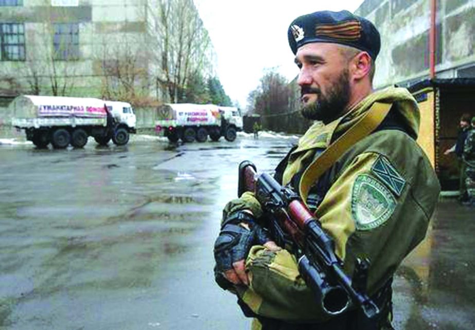 A pro-Russian-separatist patrols the street in front of Russian humanitarian trucks in Makiivka (Makeyevka) in Donetsk region, on Monday.