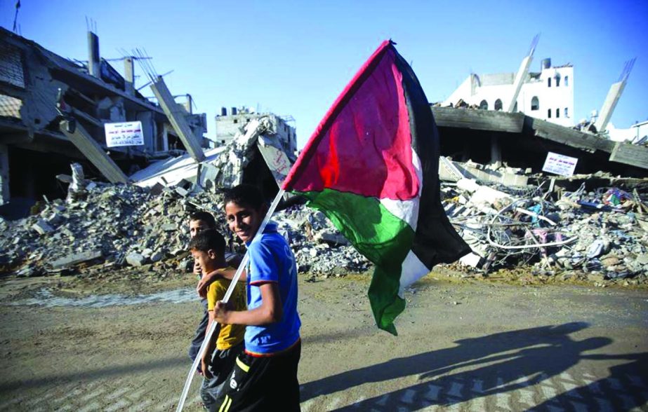 A group of Palestinian boys, one carrying the national flag, walk past destroyed houses in the Shejaiya neighborhood of Gaza City.