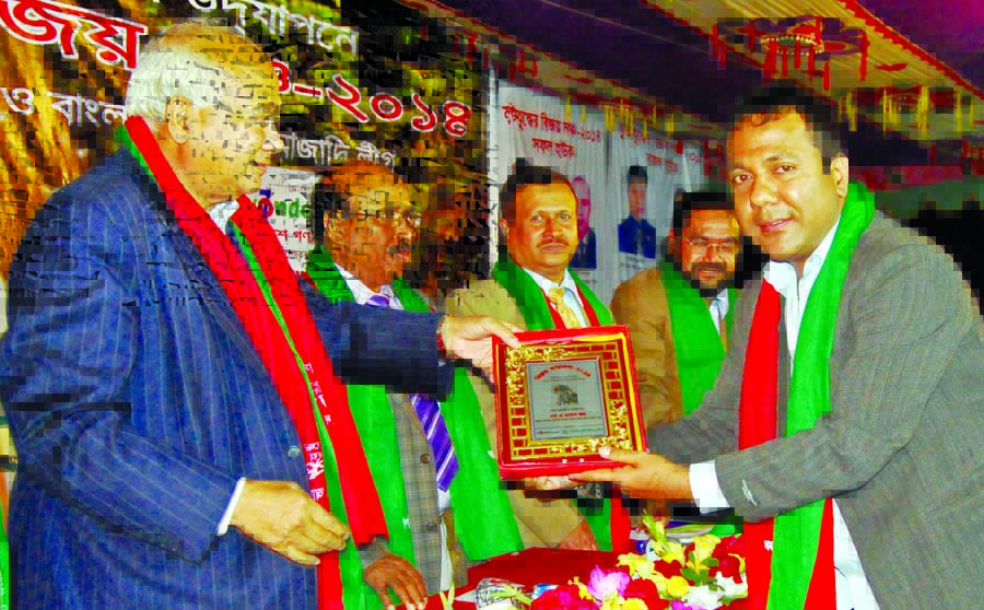 Housing and Public Works Minister Engineer Mosharraf Hossain handing over citation crest to MA Hasan Joy for his contribution in social services at Suhrawardy Udyan in the city on Tuesday.