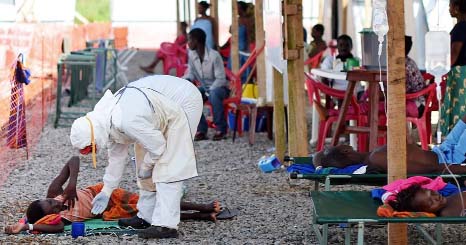 A nurse wearing personal protective equipment checks on a patient at the Kenama Ebola treatment centre run by the Red Cross Society.