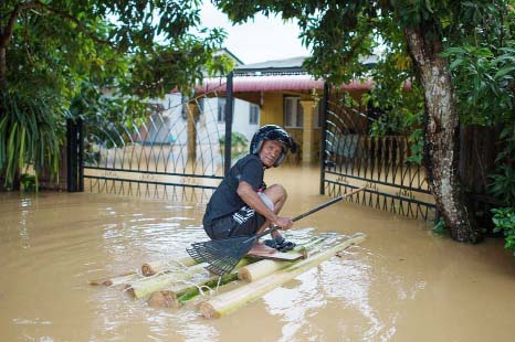 A man uses a makeshift raft to make his way to his house submerged in floodwaters in Pengkalan Chepa, near Kota Bharu on Saturday.