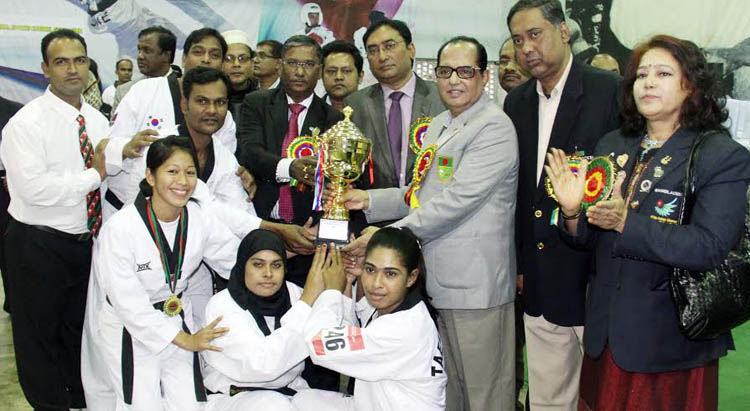 The winners of the Trust Bank National Taekwondo Competition with the chief guest State Minister for Youth and Sports Biren Sikder and the other guests and officials of Bangladesh Taekwondo Federation pose with the trophy at the Gymnasium of the National