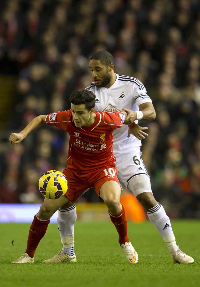 Liverpool's Philippe Coutinho (left) fights for the ball against Swansea's Ashley Williams during the English Premier League soccer match between Liverpool and Swansea at Anfield Stadium, Liverpool, England on Monday.