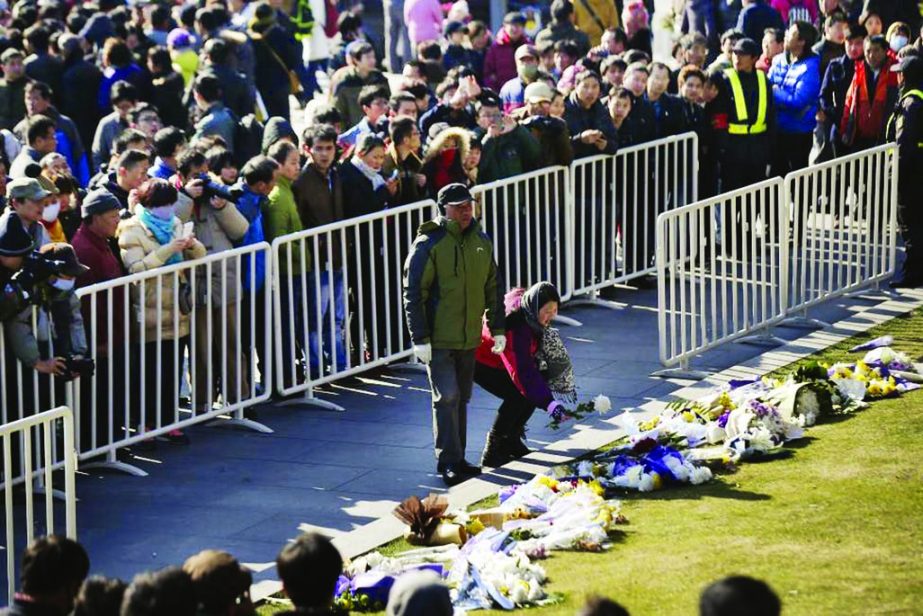 People lay down flowers during a memorial ceremony in memory of people who were killed in a stampede incident during a New Year's celebration on the Bund, in Shanghai on January 1, 2015.