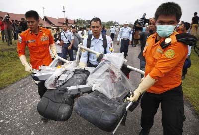 Parts of AirAsia QZ8501, recovered from the Java Sea, are carried by Indonesian Airforce and Search and Rescue crew members after they were offloaded from a US Navy helicopter at the airport in Pangkalan Bun, Central Kalimantan on Monday.