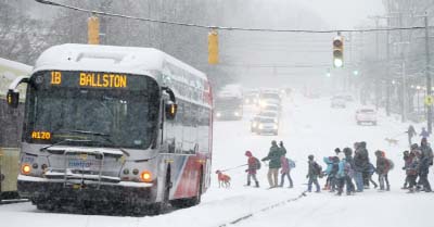 Parents lead school children past buses stopped after police closed off a stretch of Wilson Boulevard due to icy conditions in Arlington, Virginia.