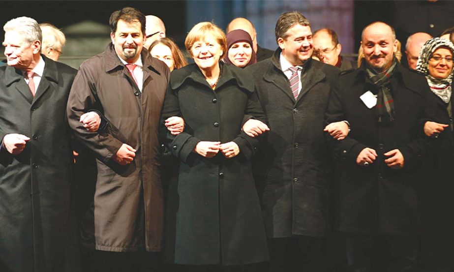 German President Joachim Gauck (left), Chairman of the Central Council of Muslims in Germany Aiman Mazyek, Chancellor Angela Merkel, Vice-Chancellor Sigmar Gabriel and representatives of religious communities in Germany link arms during a vigil organised