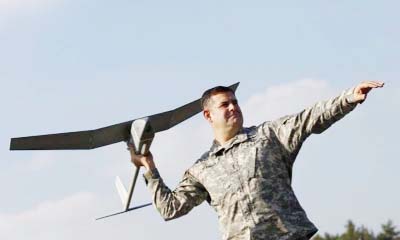 US soldier poses with 'Raven' drone during presentation by UAS at US military base.