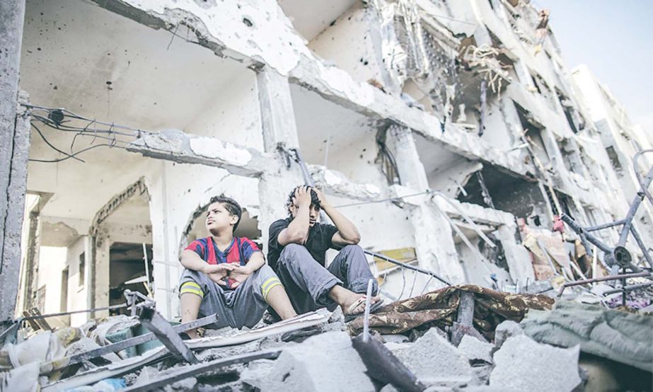 Two Palestinian brothers sit among the ruins of their destroyed house in the Gaza Strip.