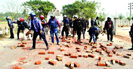 Law enforcers clearing the bricks pelted by blockaders from the highway at Matidali area in Bogra on Saturday. Banglar Chokh