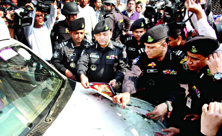 RAB Director General Benazir Ahmed pasting anti-arsonists leaflets on vehicles in cityâ€™s Gulistan area on Monday.