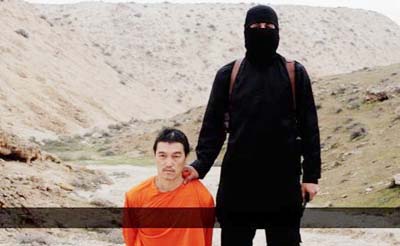 This image made from a video released by the Islamic State shows a terrorist standing next to Japanese journalist Kenji Goto before his beheading.