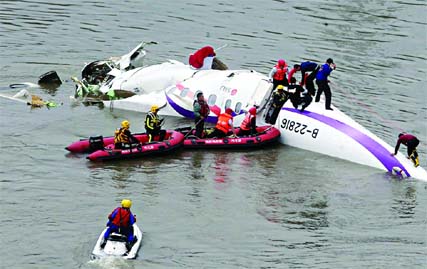 Emergency personnel approach a commercial plane after it crashed in Taipei, Taiwan. The Taiwanese commercial flight with 58 people aboard clipped a bridge shortly after takeoff and crashed into a river in the island's capital of Taipei on Wednesday morni