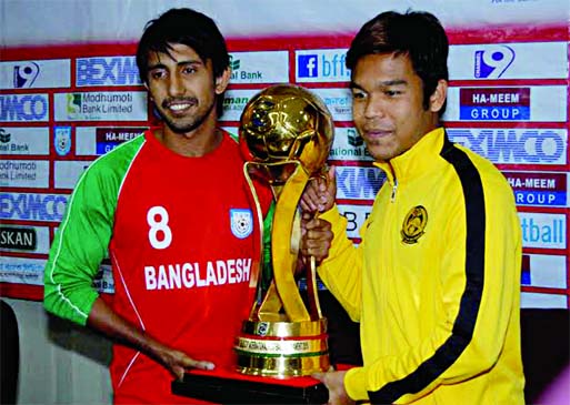 Captain of Bangladesh National Football team Mamunul Islam (left) and Captain of Malaysia Football team Nazirul Naim (right) pose with the Bangabandhu Gold Cup at the Bangladesh Football Federation House on Saturday.