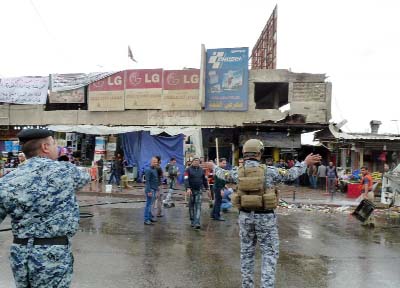 Iraqi police clear pedestrians of a street after a suicide bomber detonated explosives inside a restaurant in Baghdad Jadida, on Saturday.