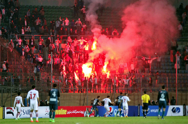 Soccer fans hold lit flares at the stand as they watch a match between Egyptian Premier League clubs Zamalek and ENPPI at Air Defence Stadium in a suburb east of Cairo on Sunday.