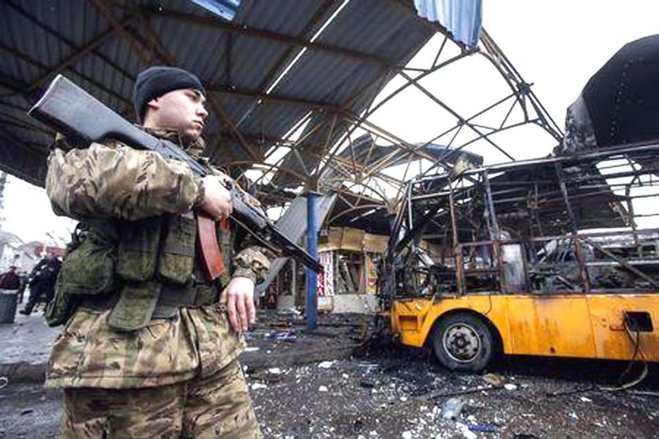 A member of the armed forces of the separatist self-proclaimed Donetsk People's Republic stands guard near a destroyed vehicle at a bus station after shelling in Donetsk, on Wednesday.