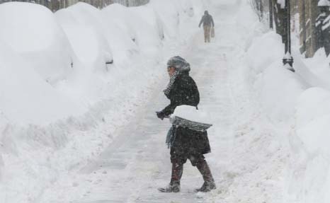 A woman shovels snow on Joy Street during a winter blizzard in Boston on Sunday.