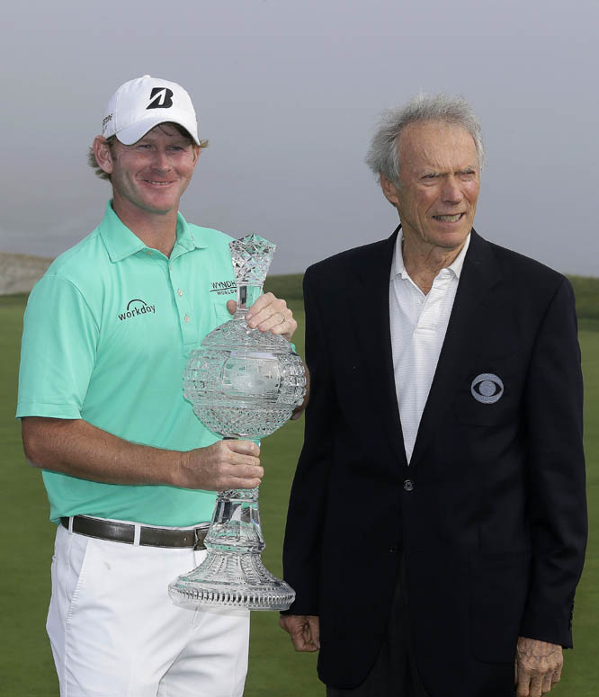 Brandt Snedeker holds his trophy and poses with Clint Eastwood on the 18th green of the Pebble Beach Golf Links after winning the AT&T Pebble Beach National Pro-Am golf tournament Sunday, Feb. 15, 2015, in Pebble Beach, Calif. Snedeker won the tournament
