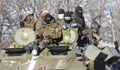 Ukrainian government soldiers sit on top of their armured vehicle driving on a road stretching away from the town of Artemivsk, Ukraine, towards Debaltseve on Tuesday.