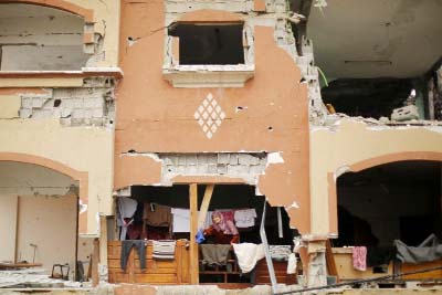 A Palestinian woman hangs out washing in her home in the town of Beit Hanun - one of 100,000 homes damaged or destroyed in the Gaza war last year.