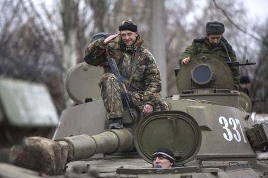 An armed man with the separatist self-proclaimed Donetsk People's Republic army salutes from the top of a mobile artillery cannon as his convoy starts pulling back from Donetsk on Saturday.