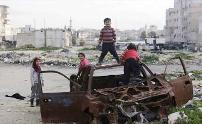 Children play on the wreckage of a burnt vehicle at al-Myassar neighborhood of Aleppo, Syria.