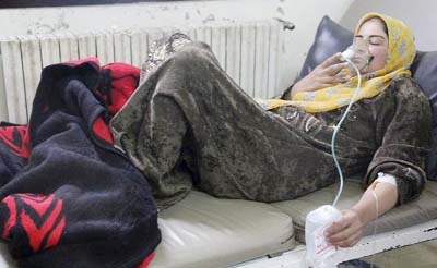 A woman, affected by what activists say was a gas attack, breathes through an oxygen mask inside a hospital in the central province of Hama.