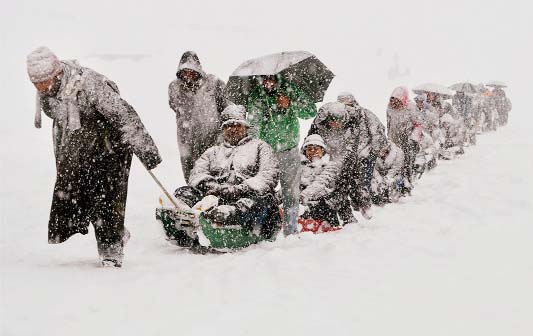 Kashmiri guides pull sleighs carrying tourists after heavy snowfall in Gulmarg..