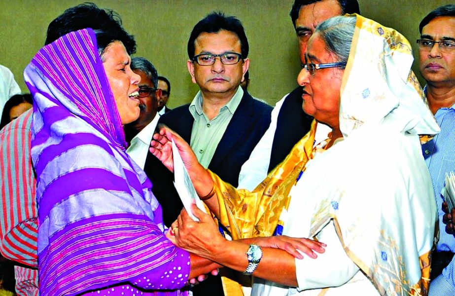 Prime Minister Sheikh Hasina distributing cheques of financial assistance to mother of a burn victim of hartal and blockade at her office on Thursday. BSS photo