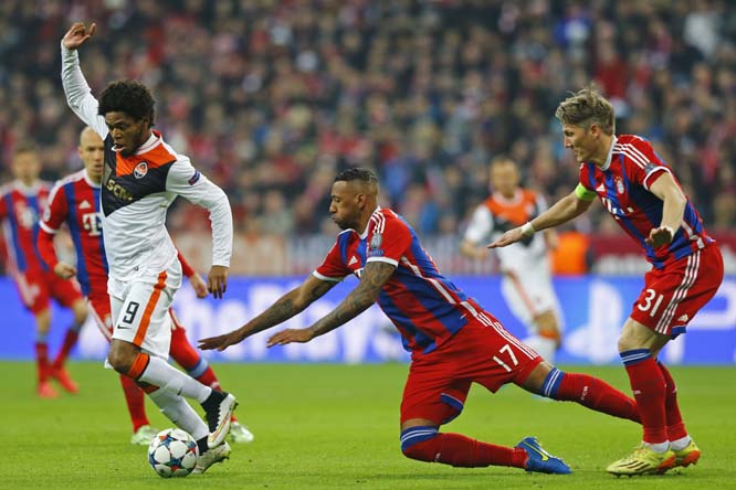 Shakhtar's Luiz Adriano, left, vies for the ball with Bayern's Jerome Boateng, center, and Bayern's Bastian Schweinsteiger, right, during the Champions League round of 16 second leg soccer match between Bayern Munich and Shakhtar Donetsk in Munich, sou
