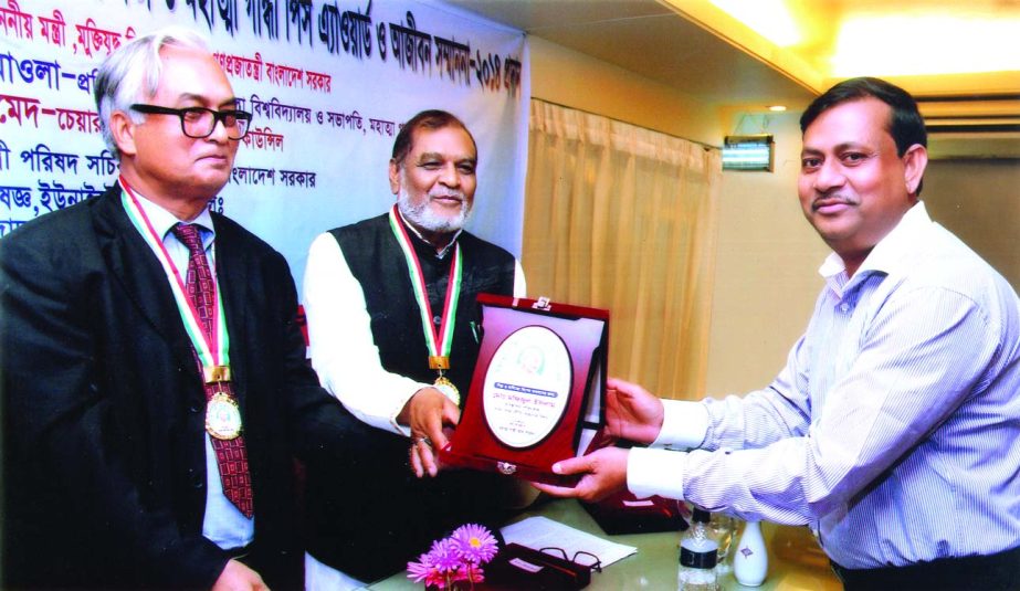 AFM Muzammel Hoque, MP, Minister of Liberation War Affairs, handing over 'Mahatma Gandhi Peace Award-2014' to Md Mofijul Islam, Managing Director of MM Neat Ware Limited, for his outstanding contribution in industrial sector and business at a city hotel