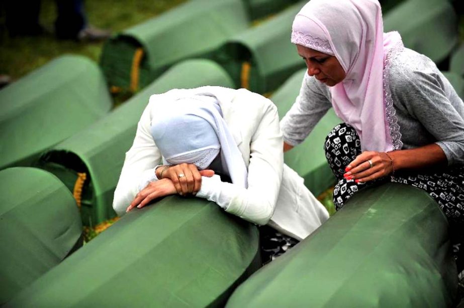 Bosnian Muslim survivors of the Srebrenica massacre cry beside the coffin of a relative at a memorial cemetery in Potocari.