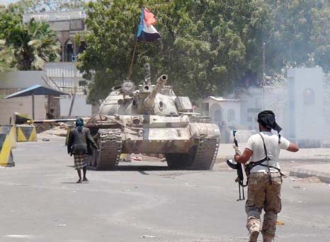 An armed Yemeni supporter of the southern seperatist movement walks towards a tank bearing the movement's flag, which they confiscated from a military depot, in the southern city of Aden.