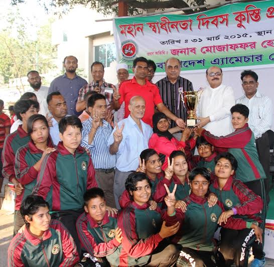 Bangladesh Ansar, the champions of the Women's Division of the Independence Day Wrestling Competition and the guests and officials of Bangladesh Amateur Wrestling Competition pose for camera at the Kabaddi Stadium on Tuesday.