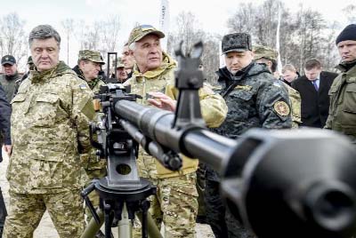 Ukraine's President Petro Poroshenko, left, followed by officials, listens to a weapons expert as he inspects weapon systems during presentation of new samples of Ukrainian-made weapons for the Ukrainian Army at a military base in Novi Petrivtsi outside