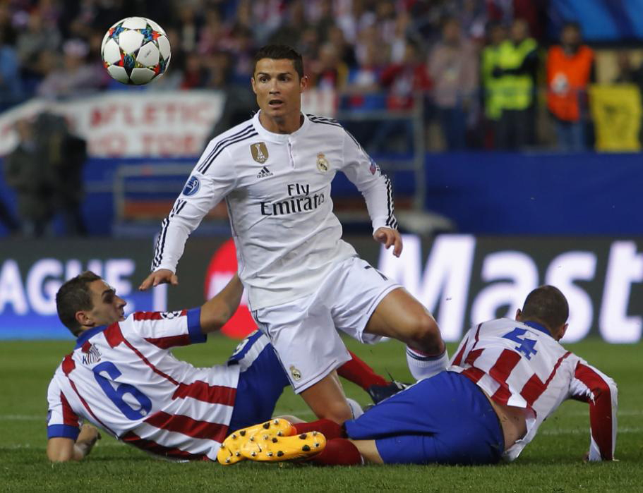 Real Madrid's Cristiano Ronaldo fights for the ball against Atletico's Koke (left) and Mario Suarez (right) during the Champions League quarterfinal first leg soccer match between Atletico Madrid and Real Madrid at the Vicente Calderon stadium in Madrid
