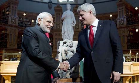 Canadian Prime Minister Stephen Harper, right shakes hands with Indian Prime Minister Narendra Modi as Harper returns a sculpture of a woman known as "parrot lady" at the Parliamentary Library on Parliament Hill in Ottawa on Wednesday