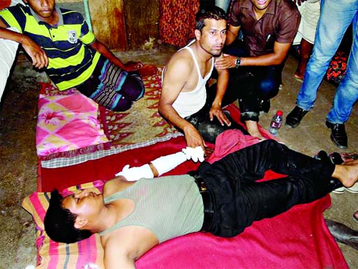 Injured bKash official Milon Roy is seen lying on the floor of Nilphamari District Hospital with bullet injury in his left arm and other bKash official is seen sitting