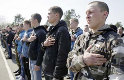 Ukrainian army recruits hold their hands over their hearts as the national anthem is played during a farewell ceremony in Kiev.