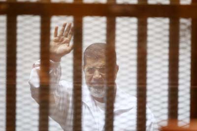 Egypt's deposed Islamist president Mohamed Morsi waves inside the defendant's cage during a trial at the police academy in Cairo.