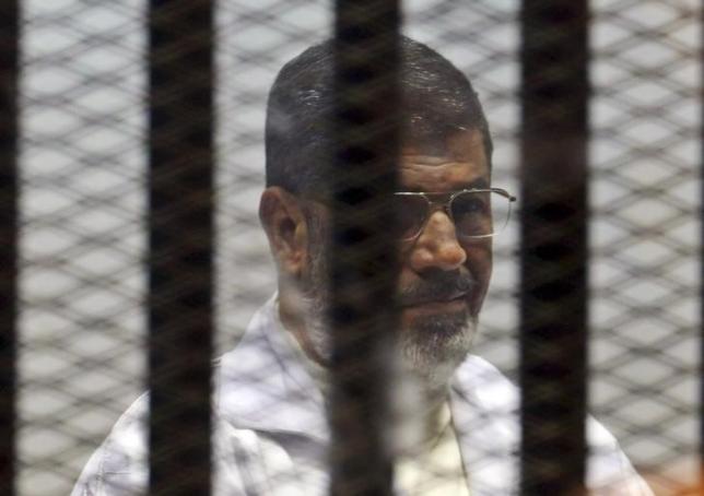 Former Egyptian President Mohamed Mursi sits behind bars with other Muslim Brotherhood members at a court in the outskirts of Cairo, December 29, 2014. ReutersAsmaa Waguih